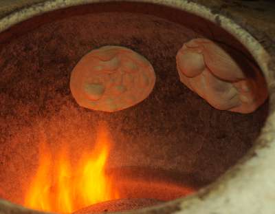 Bangladeshi Food: Layered and folded Naan flatbread baking an a gas-fired clay oven (Tandoor)