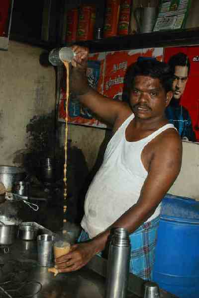 Coffee wallah (coffee vendor) cooling his drink in Madurai, Tamil Nadu (India)