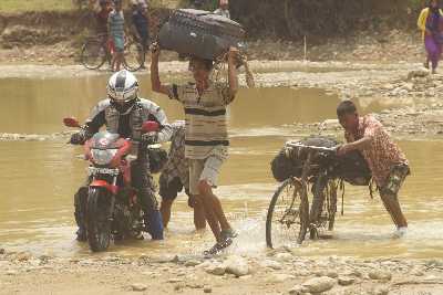 Bus travellers have to cross a stream by foot because of a collapsed bridge, Western Terai, Nepal